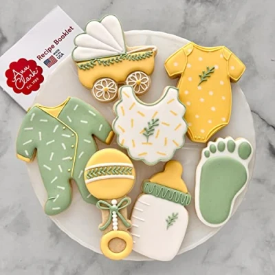 Afbeelding van Ann Clark Cookie Cutters 7 stuks uitsteekvormpjes voor babyshower met receptenboekje, romper, slabbetje, rammelaar, fles, koets en pyjama rompertje